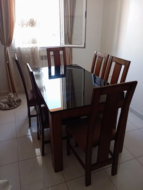 Table à manger en bois avec plateau en verre noir et six chaises.